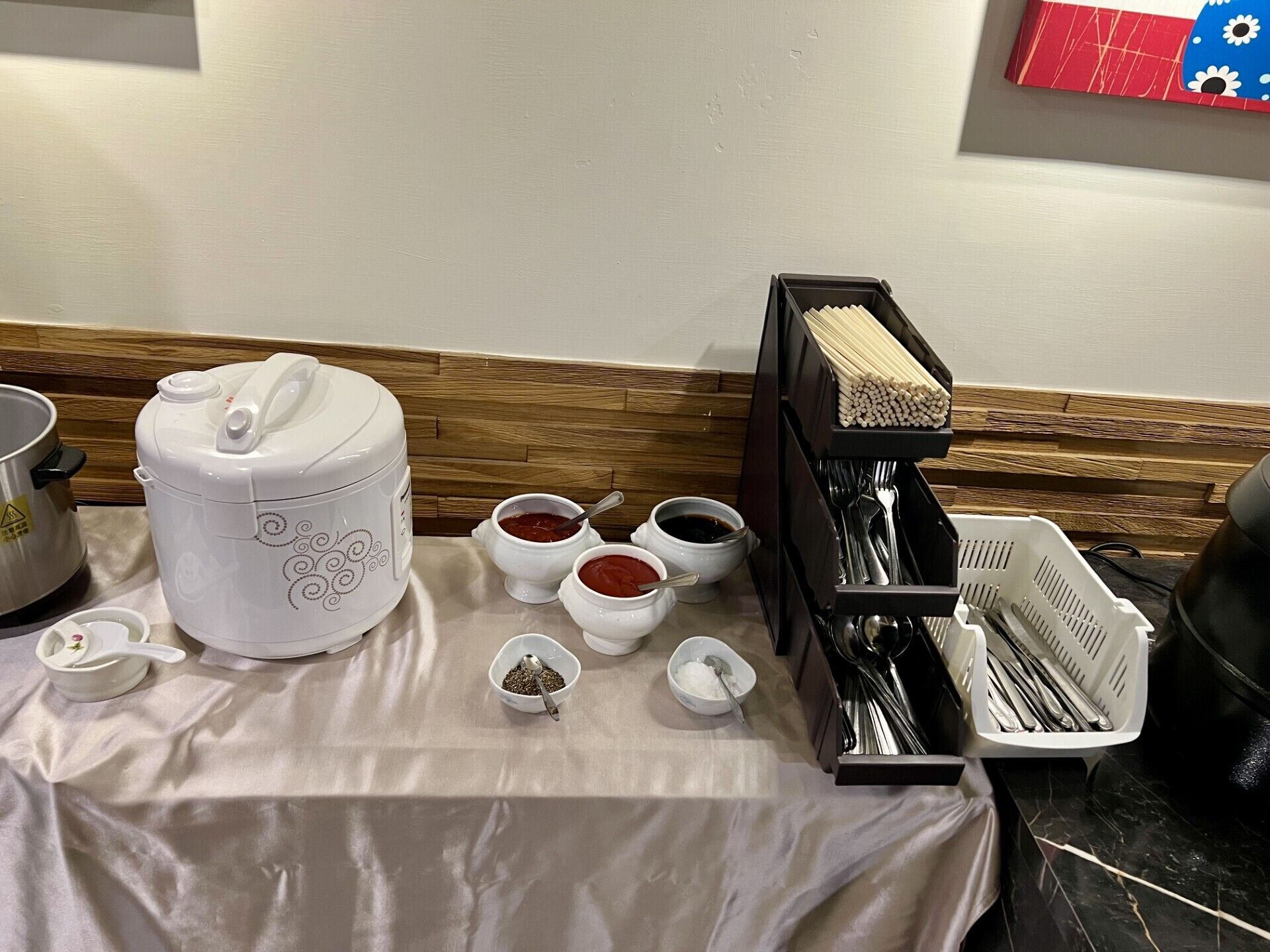 Una cocina con una cocedora de arroz, recipientes de condimentos y un organizador de utensilios.