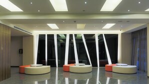 A modern lobby with a central seating area featuring circular, cushioned chairs and a glass partition with vertical lines. - City Hotel Taipei (Taipei)