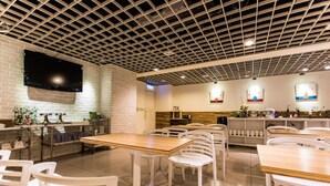 A modern restaurant with a grid-patterned ceiling, white brick walls, and a flat-screen TV mounted on the wall. - City Hotel Taipei (Taipei)