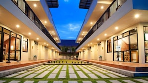 Un moderno vestíbulo de hotel con un patio central, ventanas amplias y un techo plano.