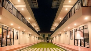 Un pasillo moderno de hotel con un patio central, con fachada de vidrio en un lado y balcón en el otro.