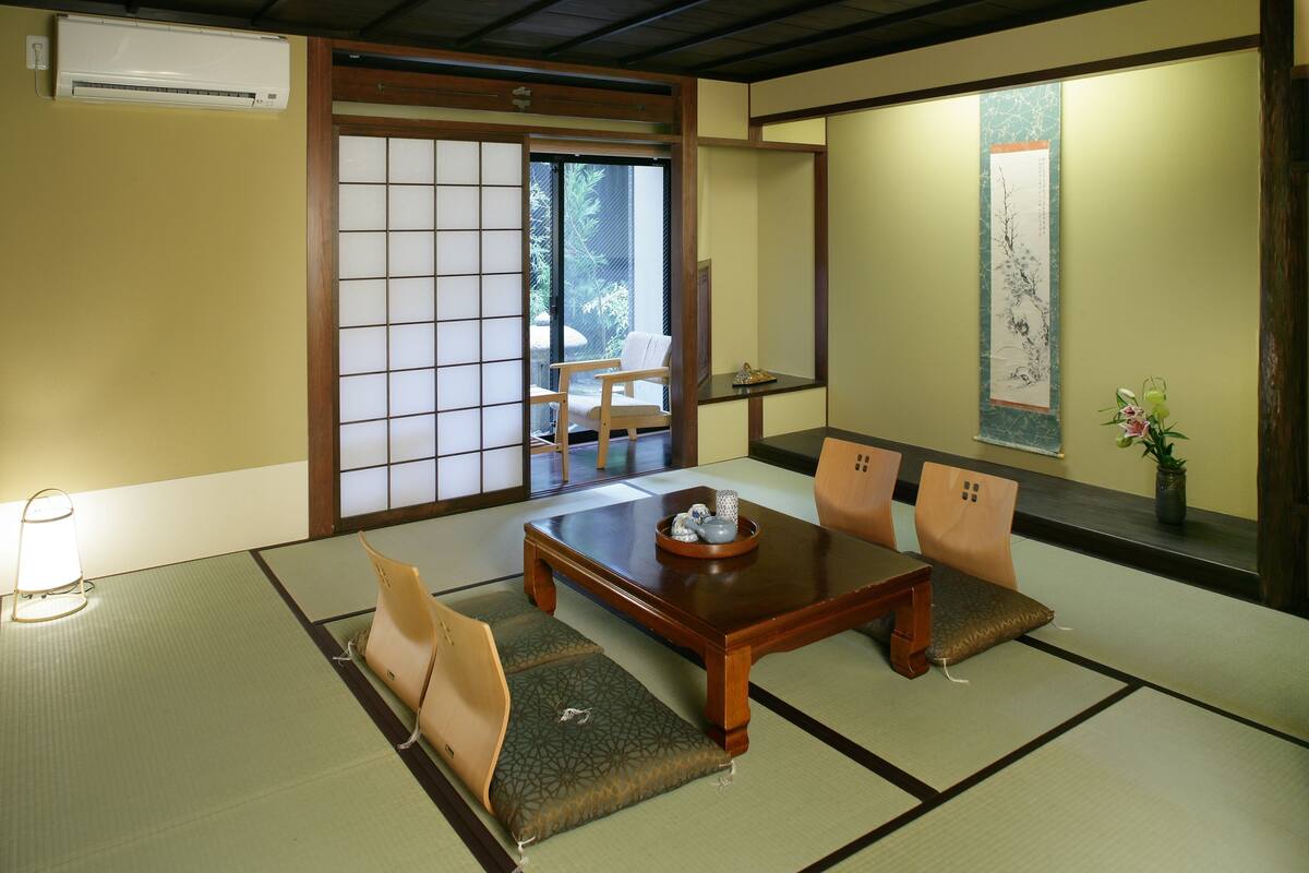 A traditional Japanese room with tatami flooring, a low table, and cushions.