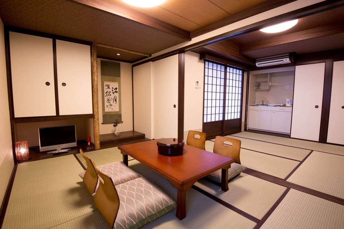 A traditional Japanese room with tatami flooring, a low table, and a television.