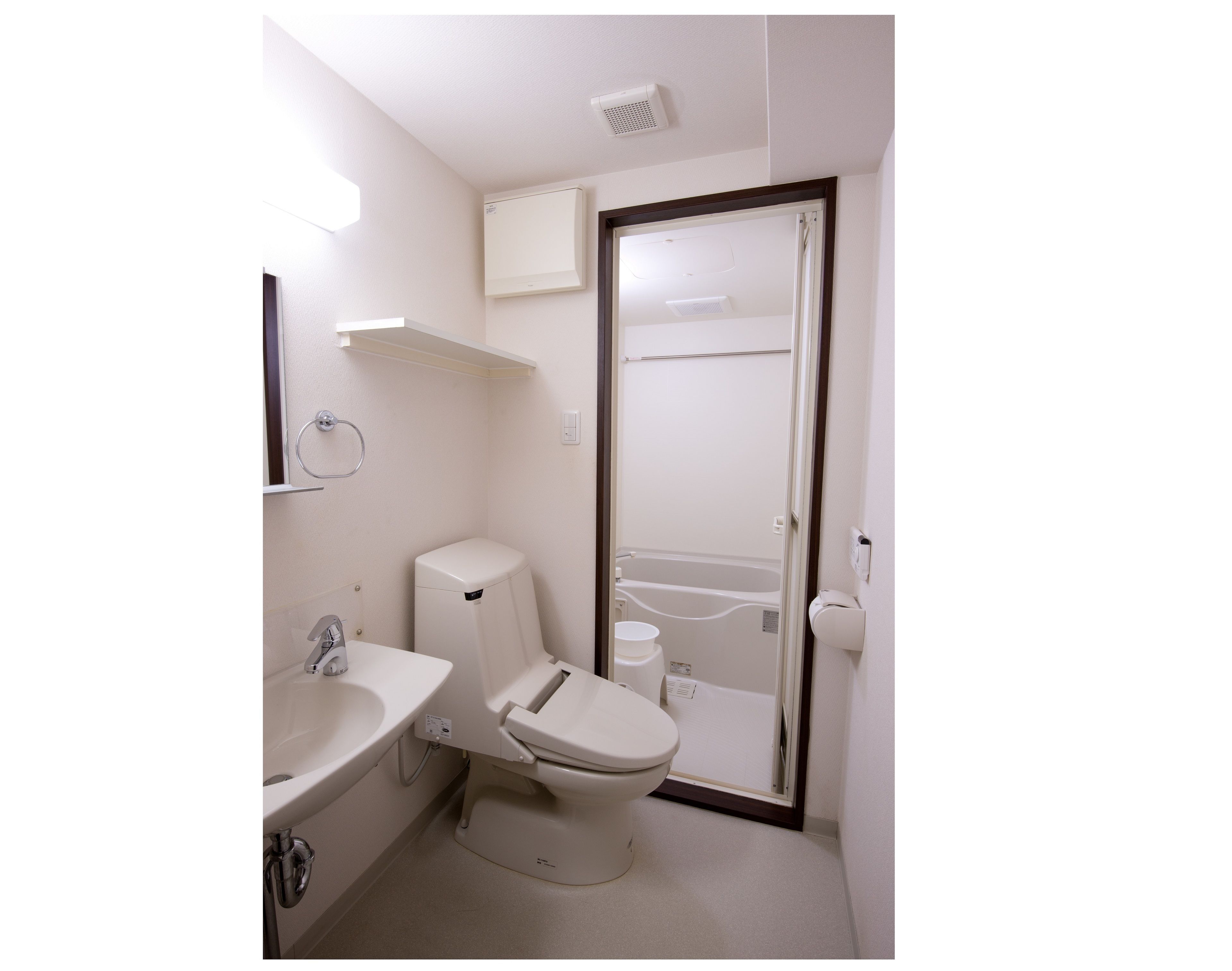 A small, clean bathroom with a toilet, sink, and shower area.