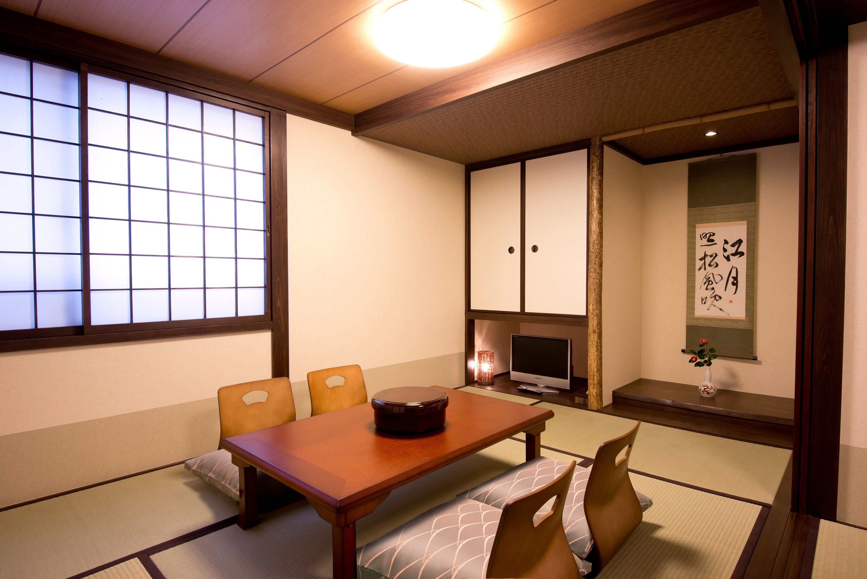 A traditional Japanese room with tatami flooring, a low wooden table, and a television.