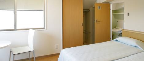 Une chambre à coucher avec un lit, une chaise, une fenêtre et un placard.