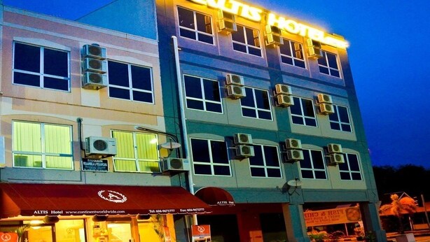Un hotel de varios pisos con un letrero llamativo que dice "ALTIS HOTEL".