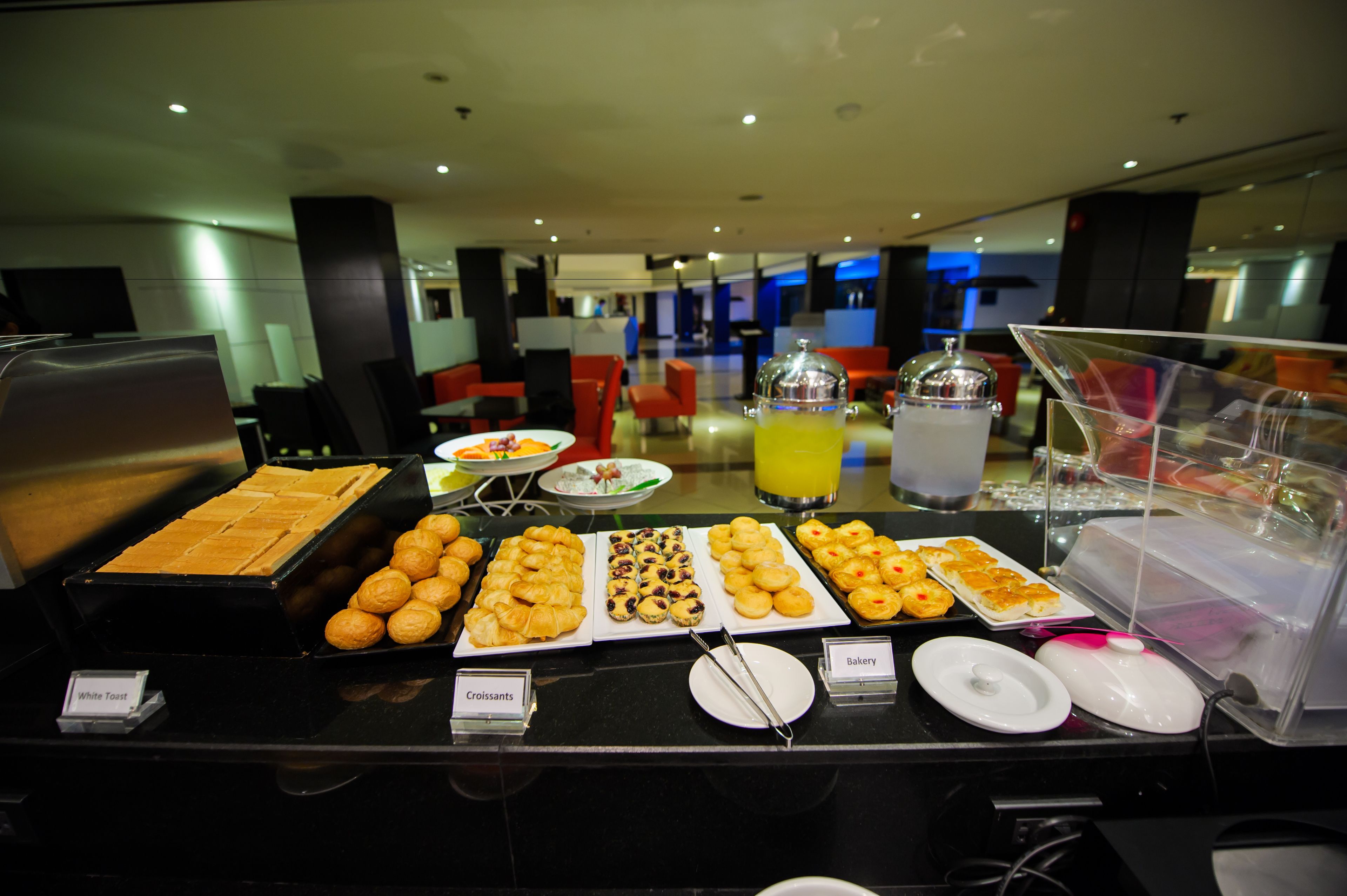 Un buffet proposant diverses pâtisseries et un verre de jus d’orange.