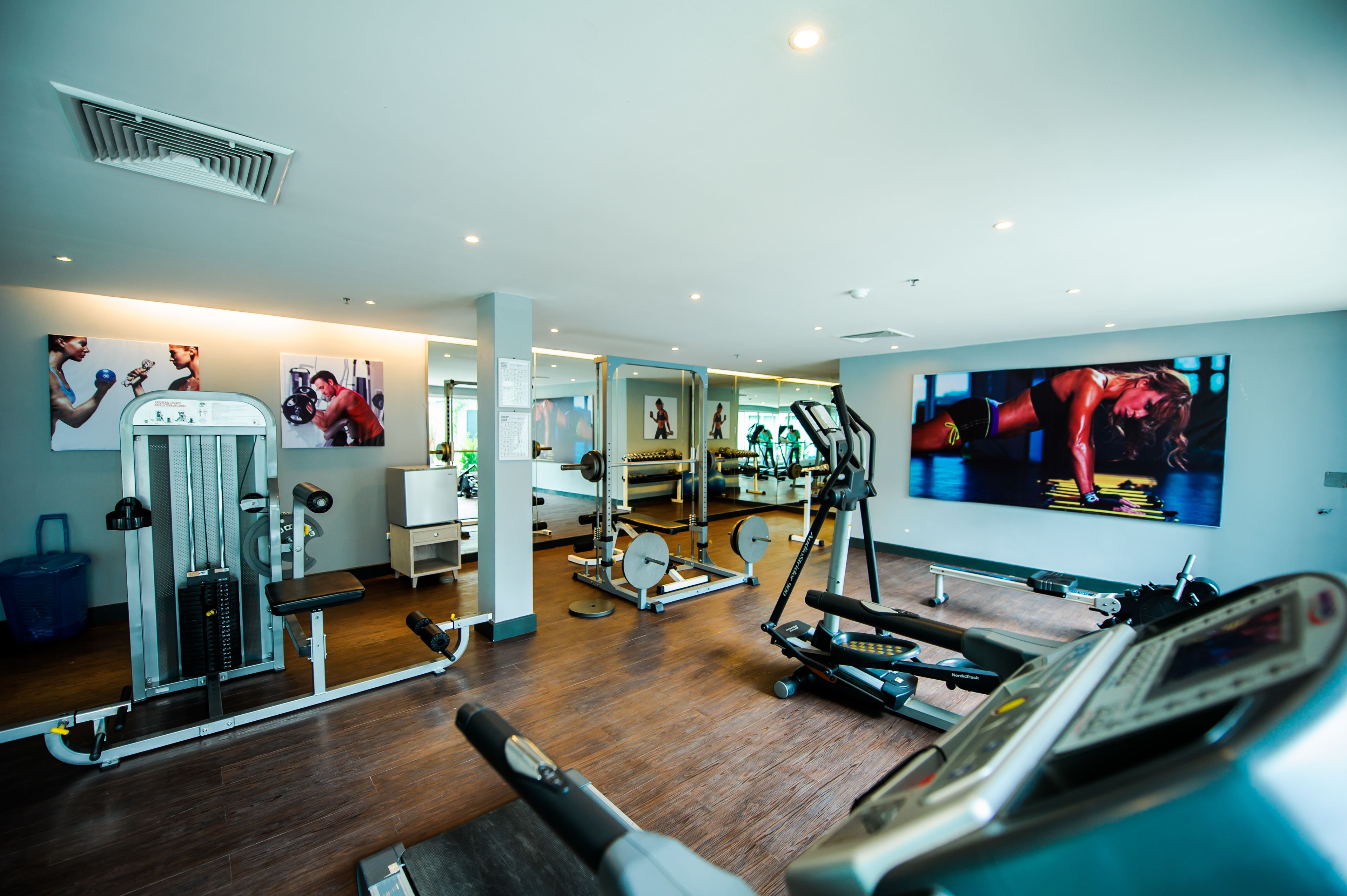 A modern gym with cardio equipment, weight machines, and mirrors.