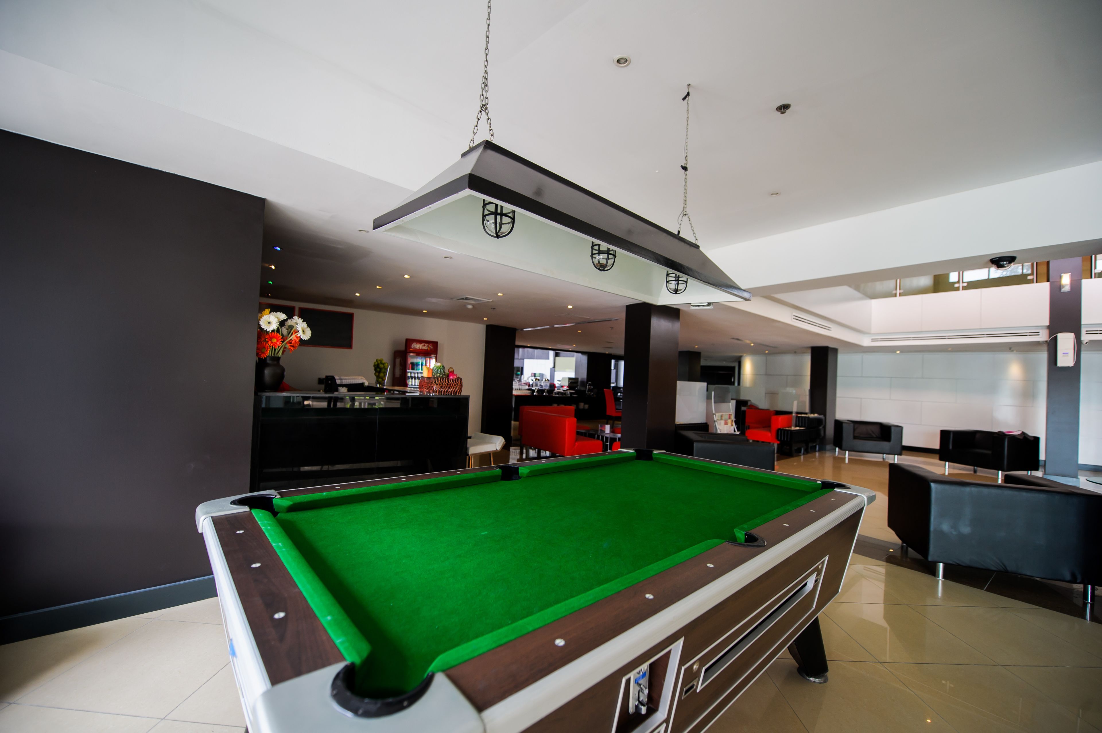 A pool table in a modern indoor setting with a bar area in the background.