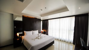 A modern hotel room with a large bed, a flat-screen TV, a nightstand, and a large window with curtains. - Hotel Selection Pattaya (Pattaya)