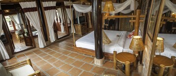 Una habitación con una cama, una silla de madera, una mesa y un espejo.