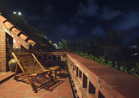 Una construcción de ladrillo con un banco y una mesa de madera, rodeada de follaje.