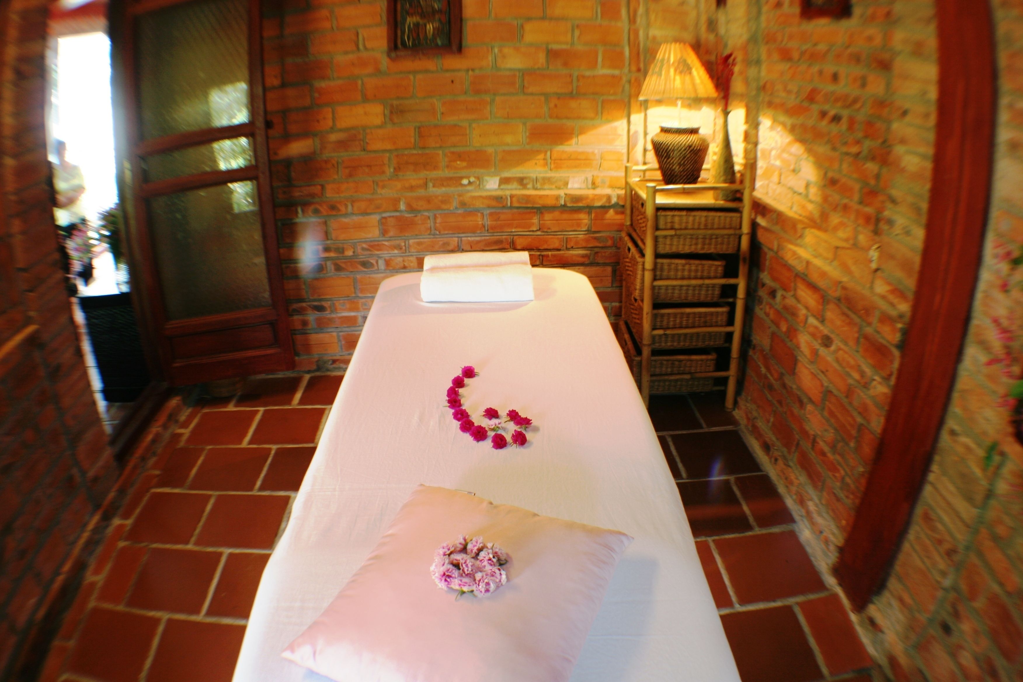A room with a massage table, a brick wall, and a window.