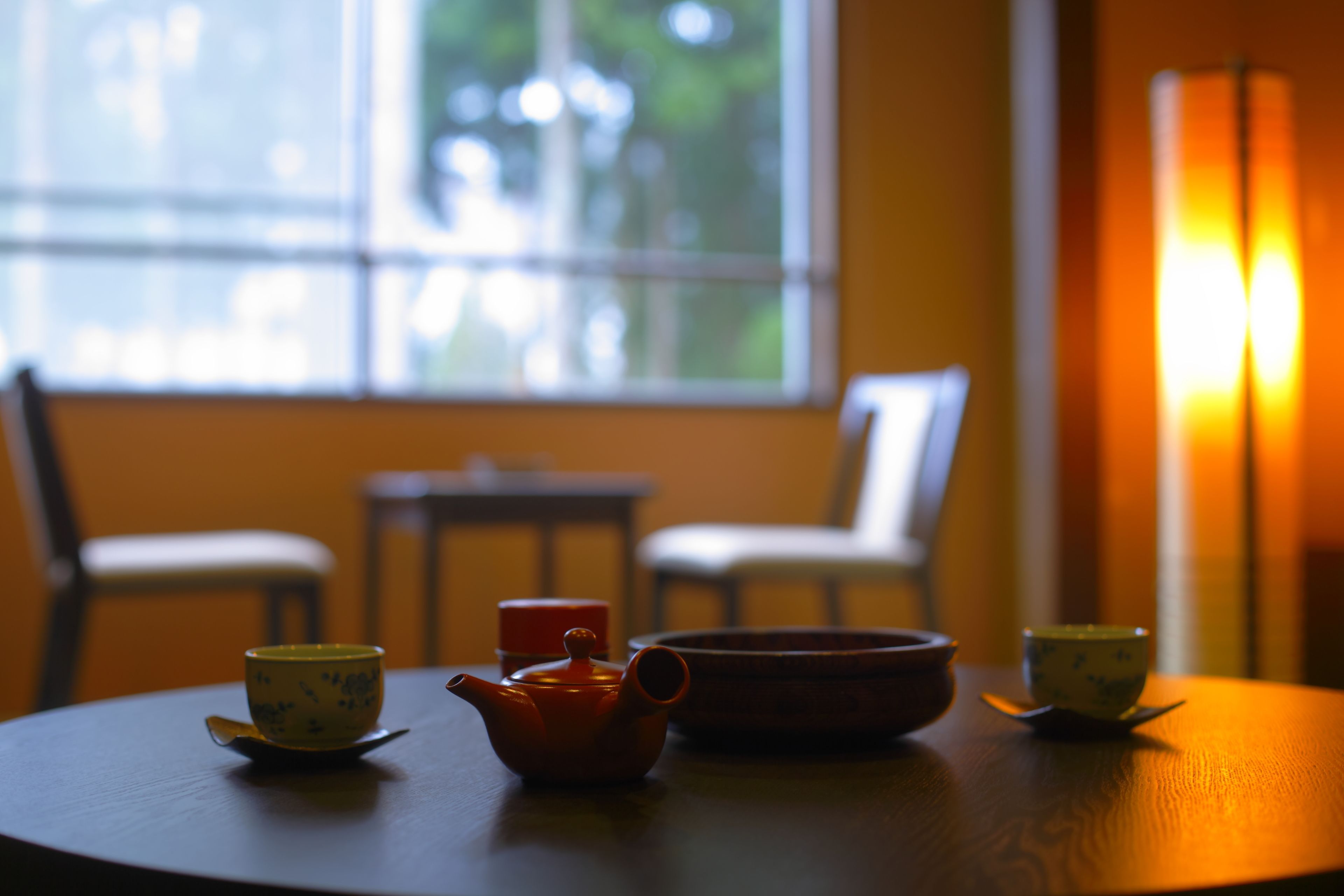 A round table with a teapot, two cups, and a bowl.
