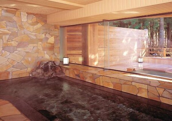 A spa area with a stone wall, a hot tub, and a wooden bench.