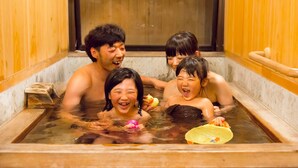 Un grupo de personas en una bañera de madera con una puerta de madera al fondo.