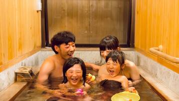 Relax in a serene onsen bath with a wooden bench and safety handle.