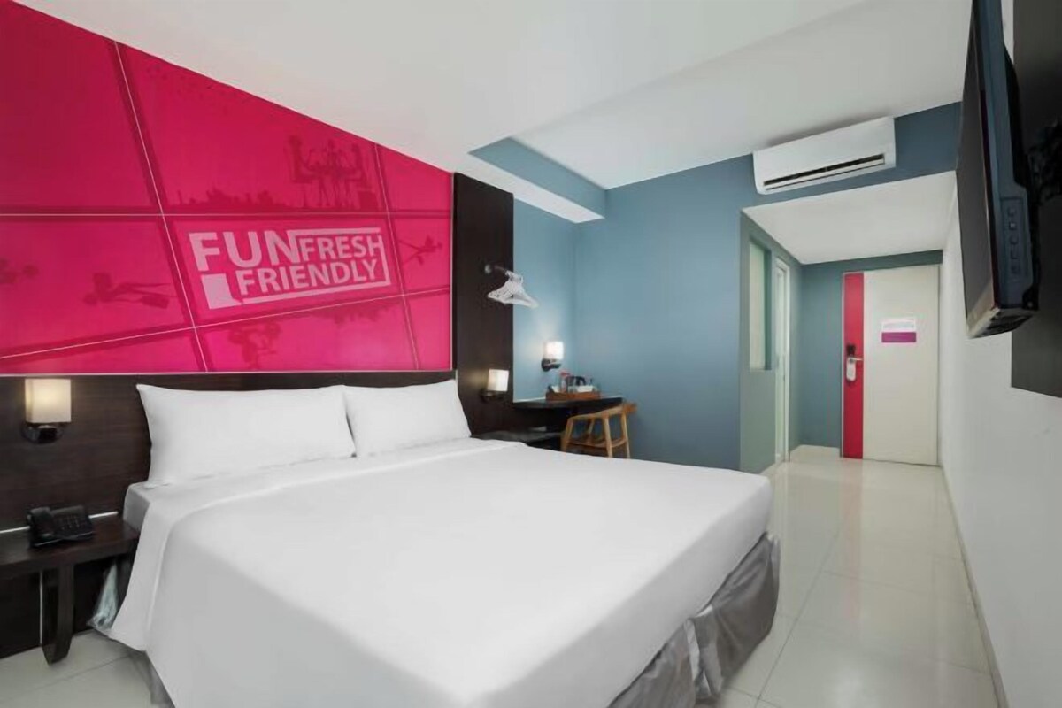 A hotel room with a large bed, a desk, and a TV.