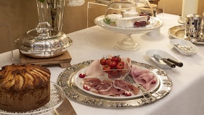 A breakfast buffet with various food items, including a cake, meats, and fruits.