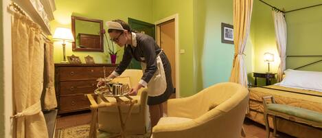 A room with a bed, a chair, a table with a lamp, and a dresser.