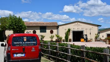 A red van parked in front of a building with a sign reading 'Cantina Tenuta di Saragano 1921'.