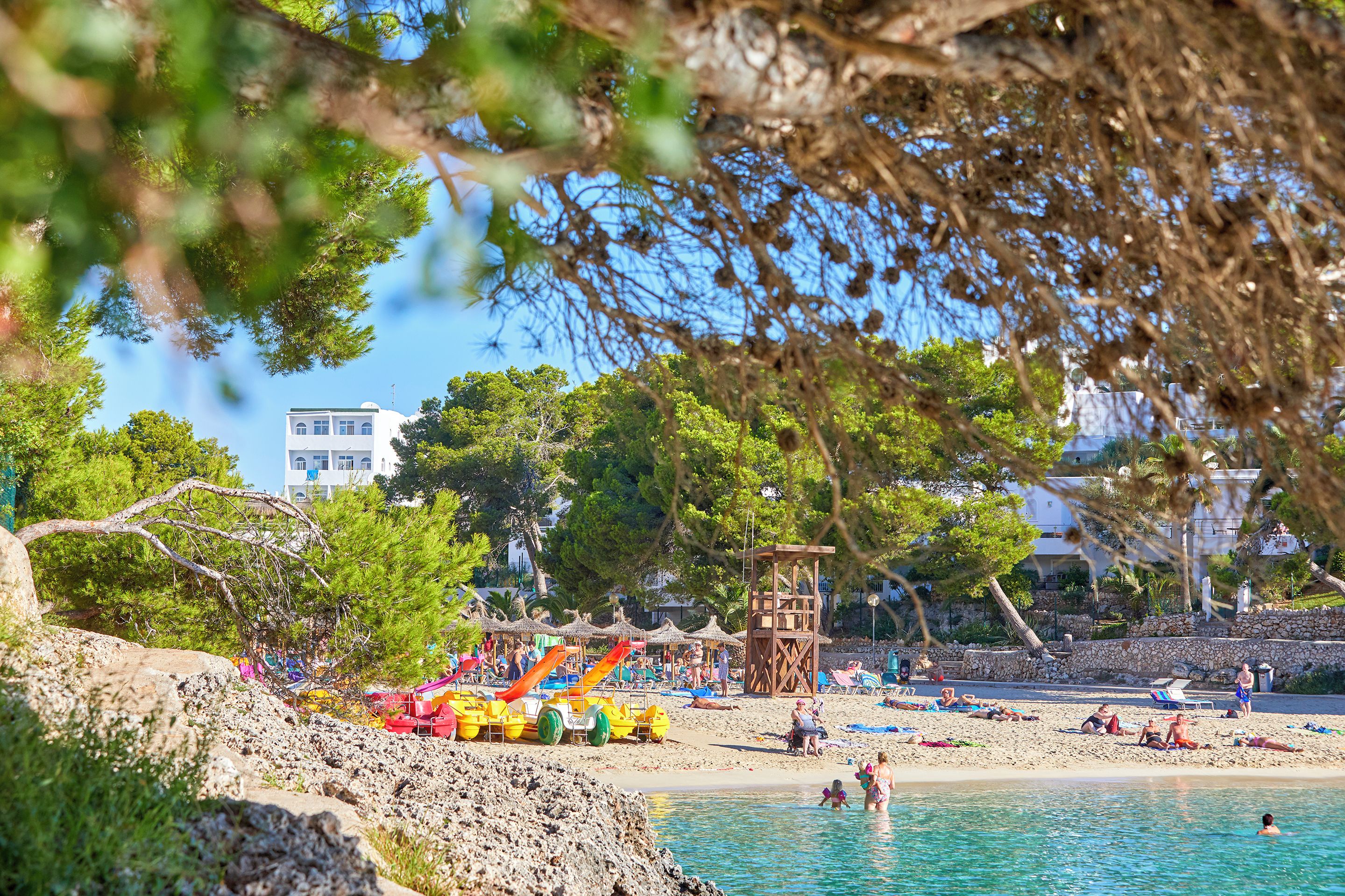 Une plage avec un toboggan aquatique, des parasols et des gens qui se détendent.