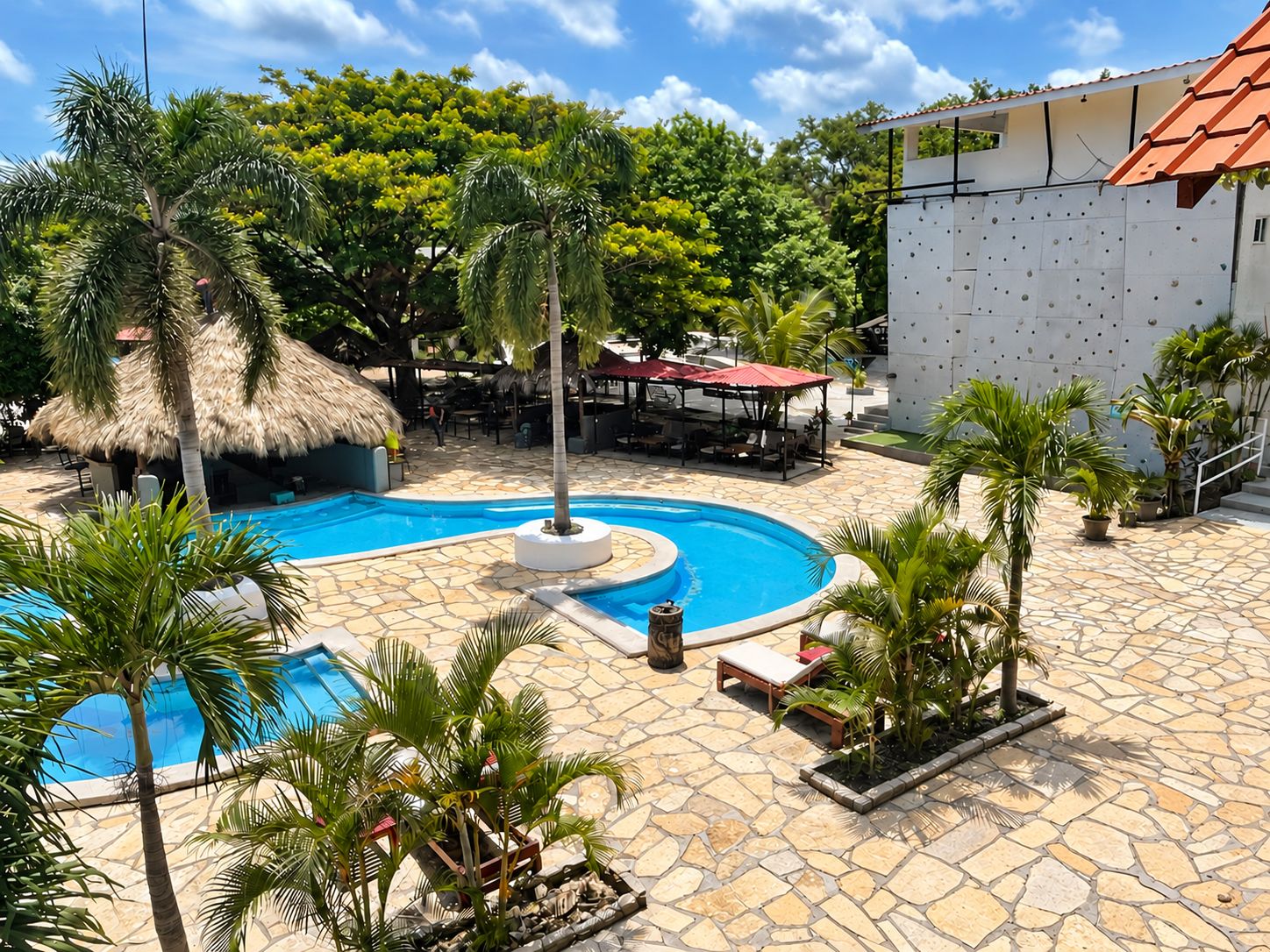 A pool area with a circular design, surrounded by palm trees and lounge chairs.