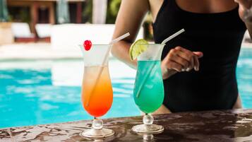 Two cocktails on a table by a poolside.