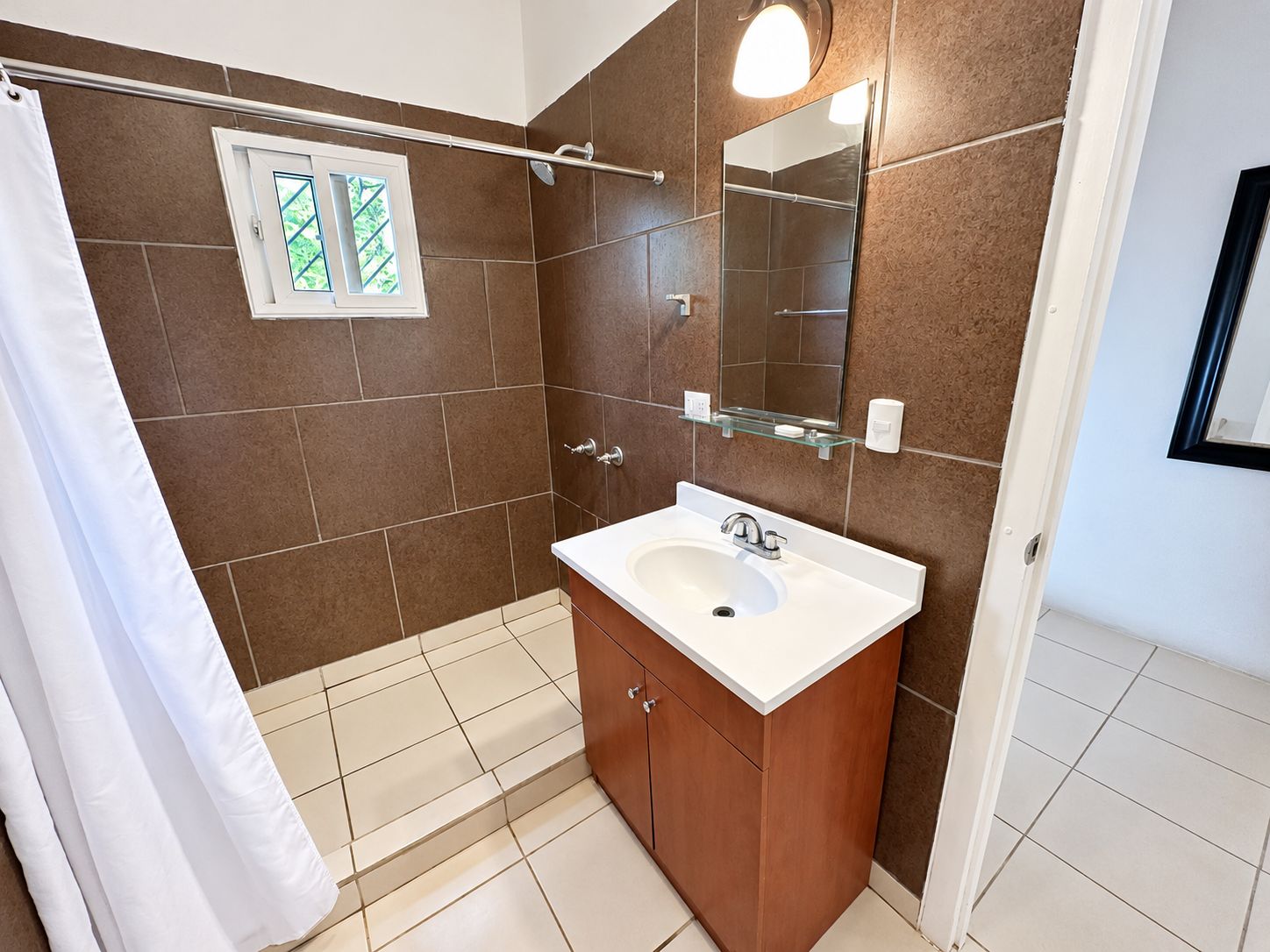 Un baño con ducha, lavabo y espejo.