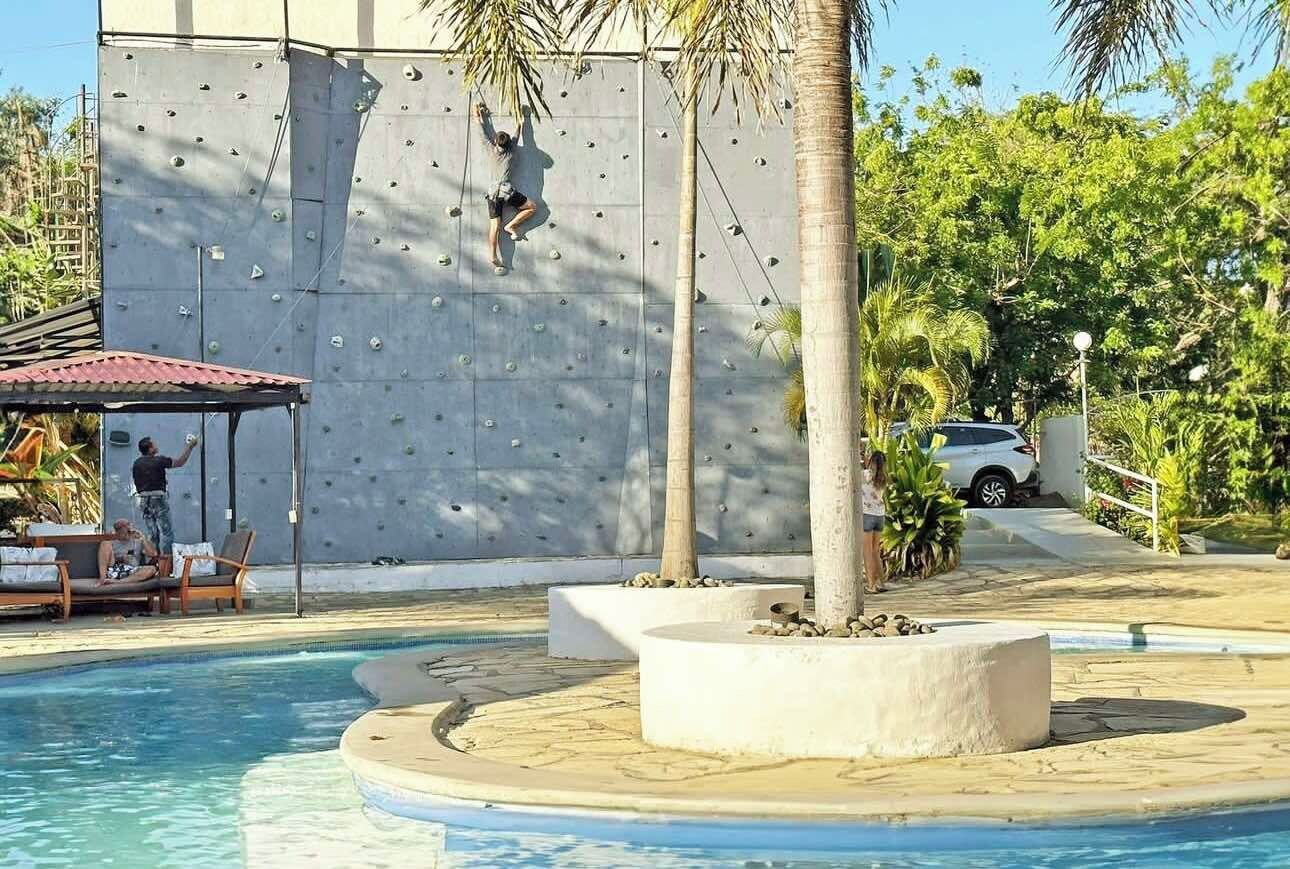 Un mur d’escalade avec un espace piscine et des chaises longues.