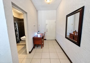 A hallway with a wooden desk, a chair, a white door, and a large mirror on the wall. - Surf Ranch Hotel & Resort (San Juan del Sur)