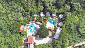 An aerial view of a resort with multiple buildings, a swimming pool, and a large tree. - Surf Ranch Hotel & Resort (San Juan del Sur)