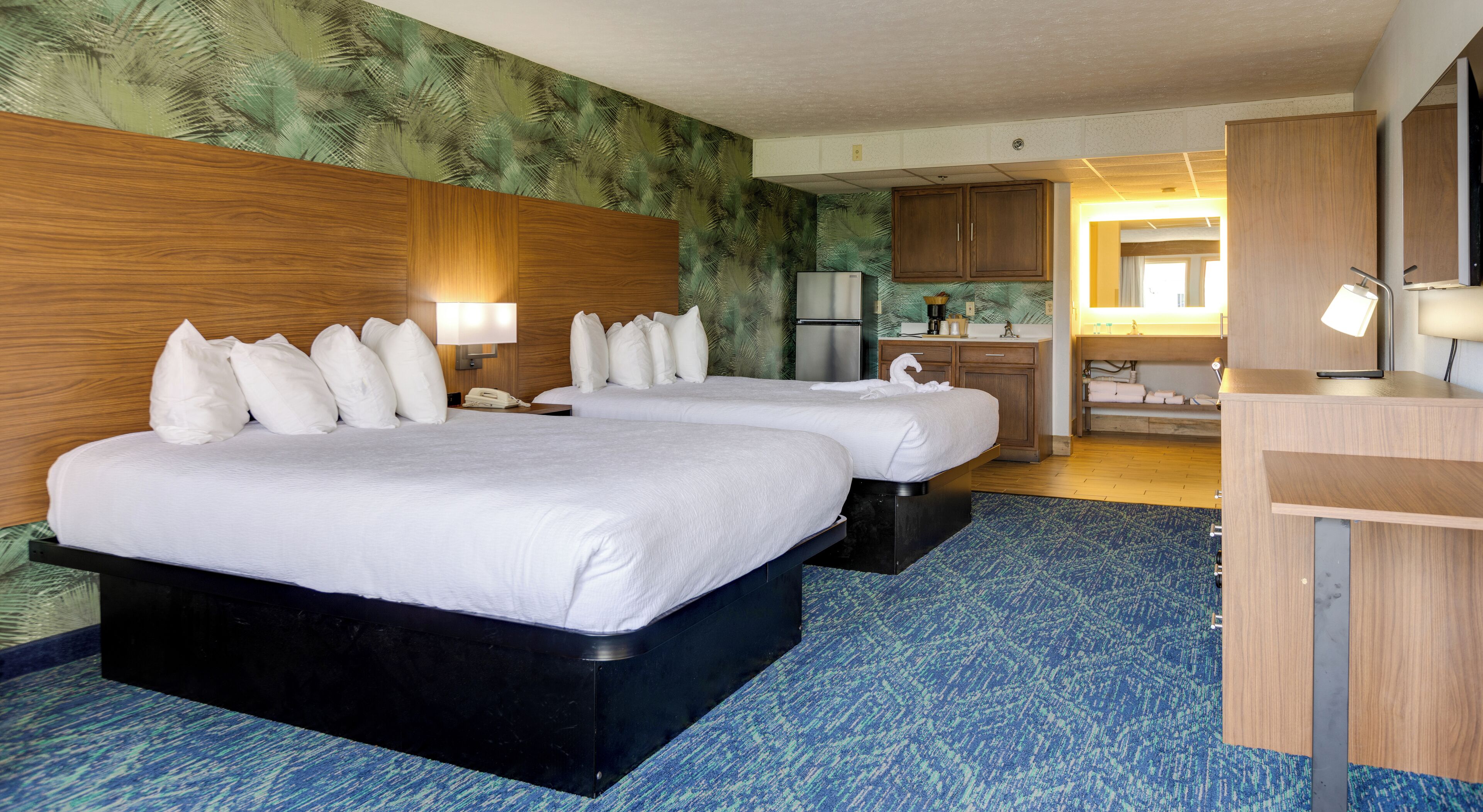 Une chambre d’hôtel avec deux lits, une kitchenette, un bureau et une salle de bain.