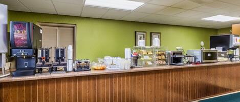 A breakfast bar with coffee machines, a refrigerator, and a microwave.