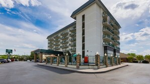 A multi-story hotel with a central tower, a covered parking area, and a fenced courtyard. - Park Grove Inn (Pigeon Forge)