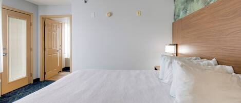 Hotellihuone, jossa on suuri sänky, puinen pääty ja näkymä käytävään.