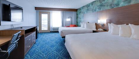 A hotel room with two beds, a desk, a chair, a TV, and a large window.