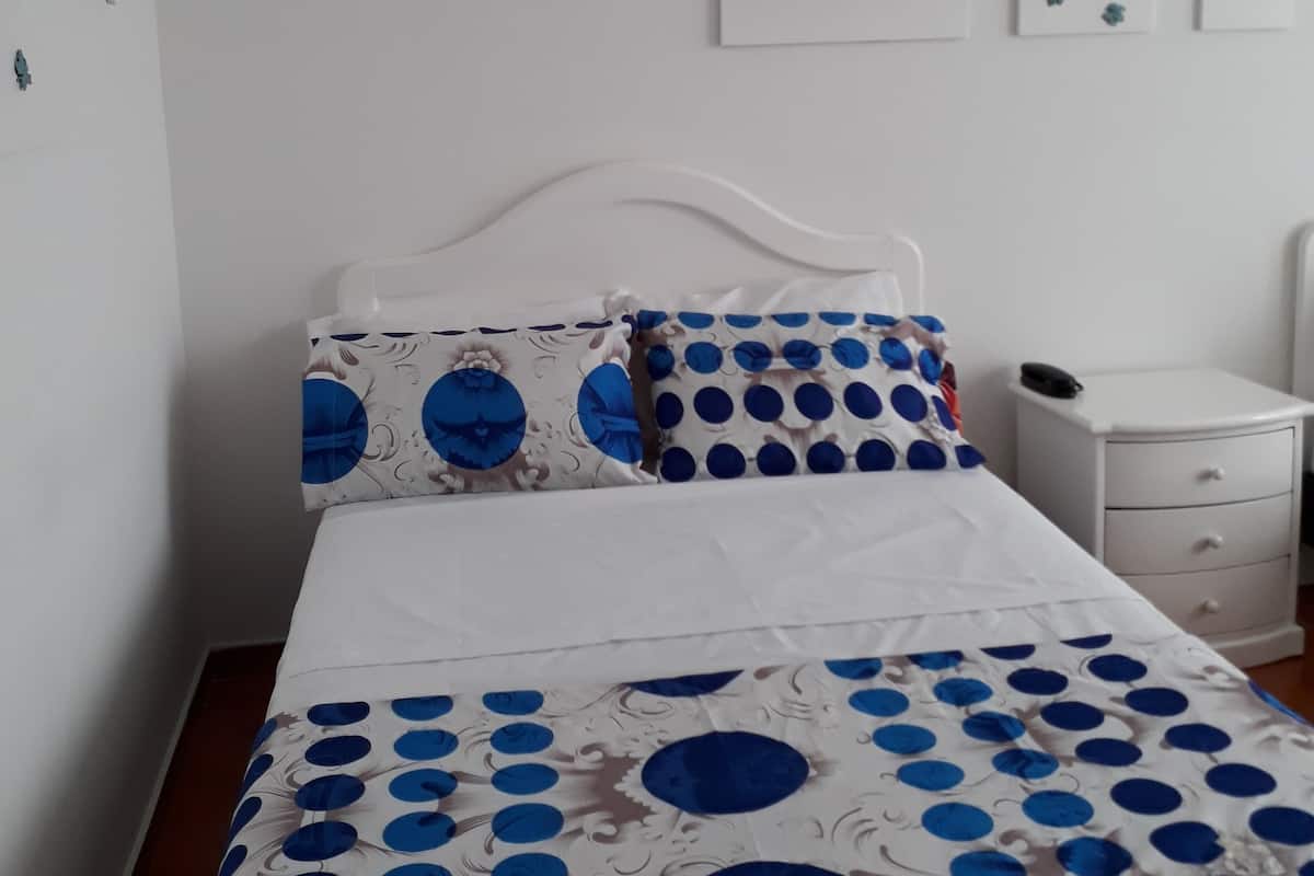 Une chambre à coucher avec un lit, une table de chevet et un mur orné de trois tableaux encadrés.