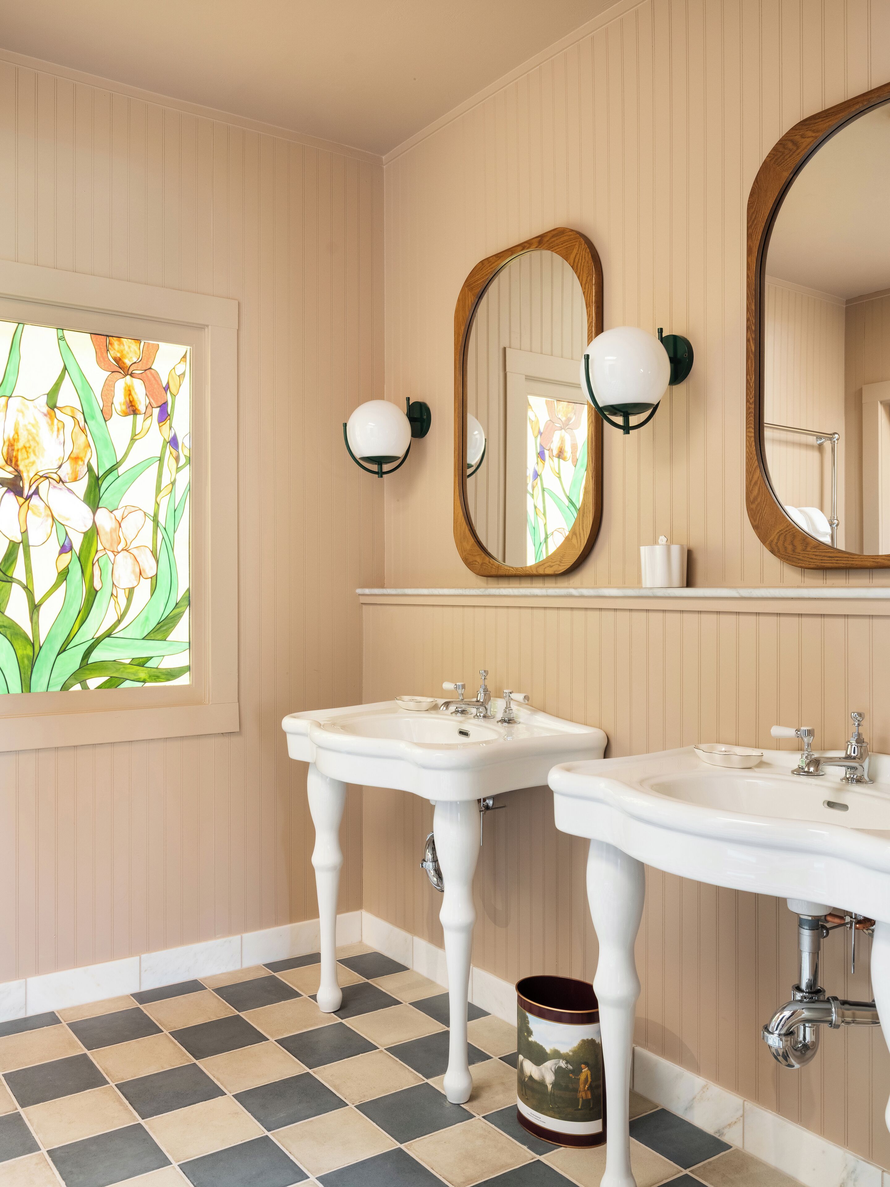 A bathroom with two sinks, a large mirror, and a stained glass window.