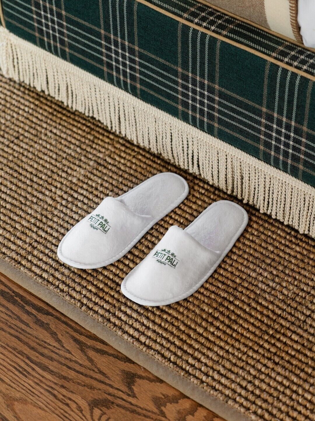Witte pantoffels met een logo op een geweven mat.