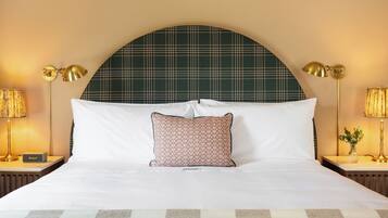 Habitación de hotel con una cama grande, dos mesitas de noche, un tapete de cuadros y un cabecero escocés.