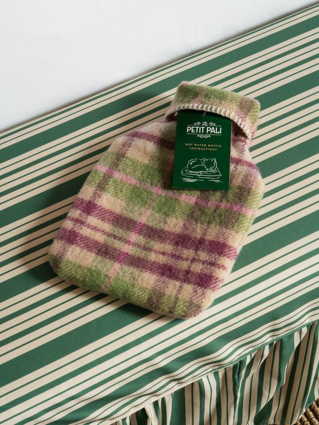 A folded, striped blanket with a tag labeled "Le Petit Pali" on a striped pillow.