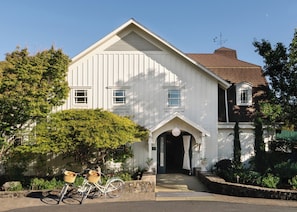 A white building with a gabled roof, a reception area, and a bicycle parked outside.