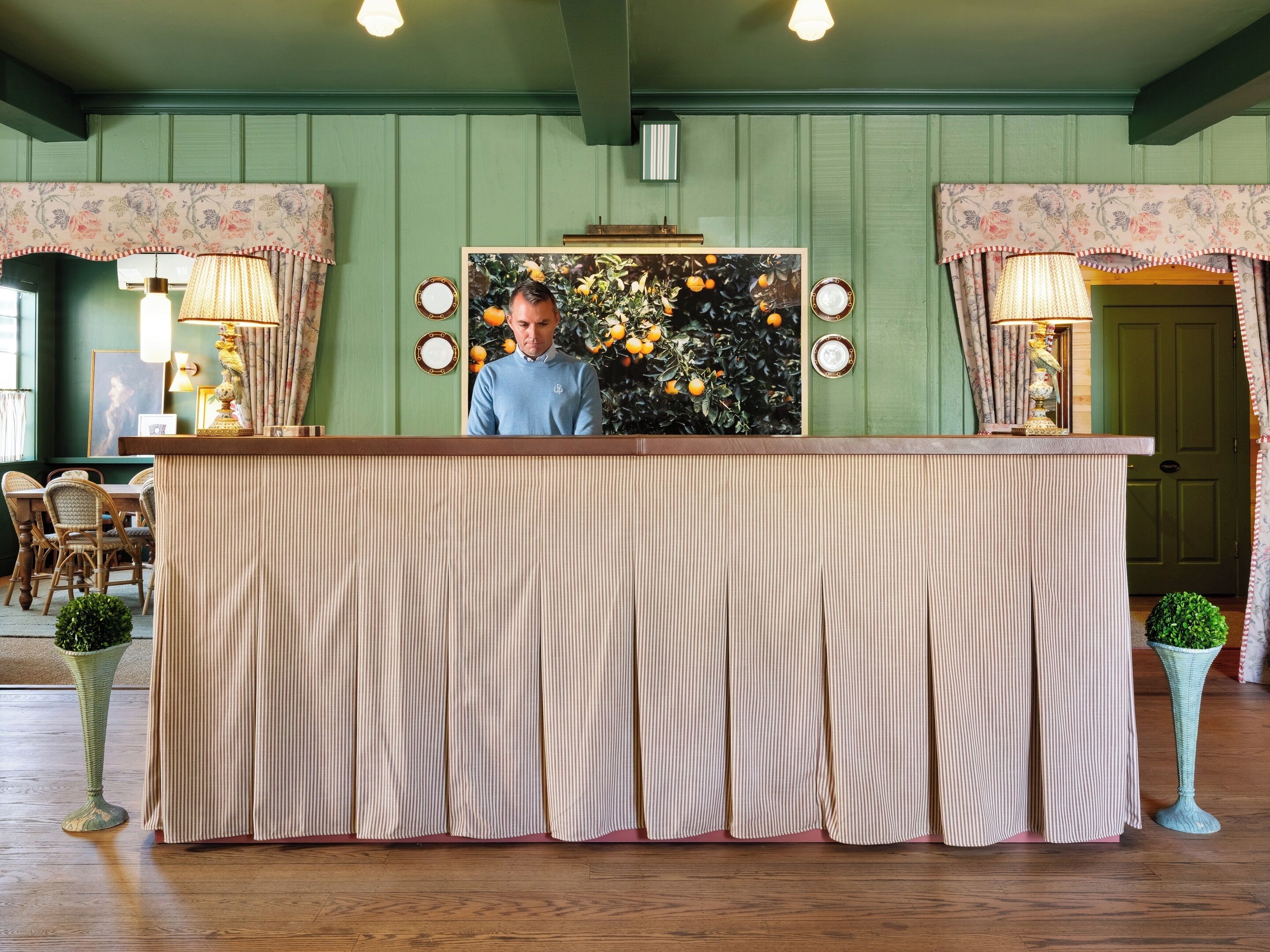 A reception desk with a striped curtain, a mirror, and a floral wall decoration.