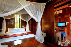 A room with a bed under a canopy, wooden walls, a television, and a small table with a plant.