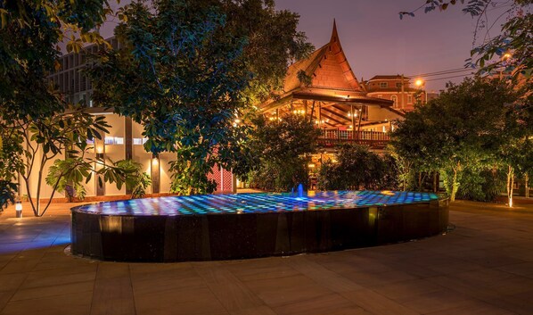 A courtyard with a water feature and a building with a distinctive roof.