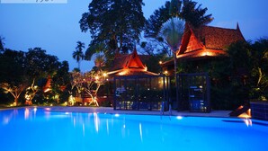 A swimming pool with a glass enclosure and a traditional building with a red roof. - Sugar Hut 1984 (Pattaya)