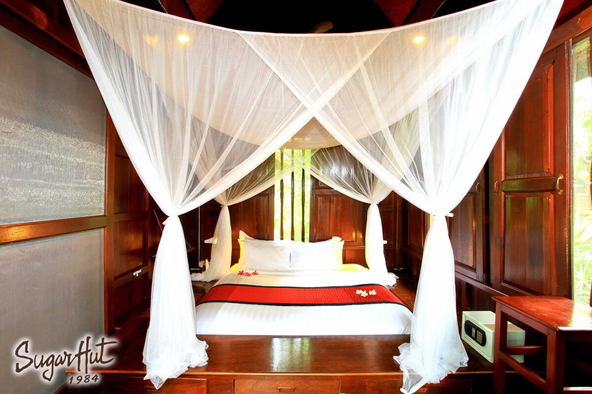 A bed with a canopy, wooden walls, and a bedside table.