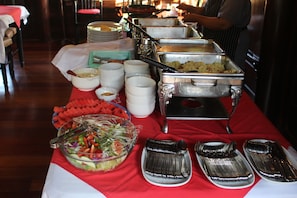 A buffet setup with various food items and serving utensils.